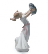Love is in the air. An infatuated young girl hold her puppy at arm's length, taking in all his cuddly cuteness in classic Lladro porcelain.