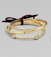 A set of three subtly textured golden bangles, each a little different, with undulating edges and shimmering rhinestones.GlassBrassDiameter, about 2½Imported