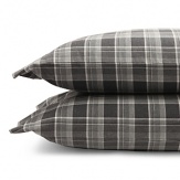 Inspired by the refined polish of menswear, this relaxed collection pairs solid brushed cotton and twill with faux suede trim and plaid. Sheets and pillowcases are in a soft cotton bold plaid in a grey and white palette.