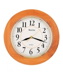 Simply classic. A timeless piece for any room, this wall clock by Bulova features a round, honey-finished wooden frame and bright gold tone bezel. White dial displays easy-to-read numerals and three hands.