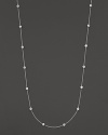 A long white gold chain is spaced with fifteen bezel-set, diamond stations.