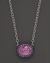 Sterling silver chain necklace adorned with an oval pink corundum pendant with amethyst pave frame. By Judith Ripka.