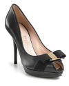 Ladylike leather peeptoe pumps with a classic Ferragamo bow and logo plate at toe.