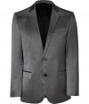 Elegant jacket in fine, grey cotton and synthetic fiber blend - Fabric has a slight, sleek sheen - Single breasted blazer style with two-button closure - Small collar and slim lapels - Two front flap pockets, single chest pocket - Side vents at rear - Modern silhouette is straight and slim - A polished, slick staple in any wardrobe - Dress up with suit trousers and a button down, or pair with jeans and a t-shirt for a more casual look