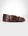 A slim leather belt is embellished with an antiqued brass buckle for a classic, timeworn aesthetic.