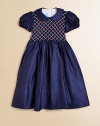 Shimmering silk shantung party dress is utterly exquisite, with a smocked front bodice detailed with delicate latticework embroidery.Peter Pan collarShirred waistShort puff sleevesBack buttonsBack-tie sashSilkDry cleanImported