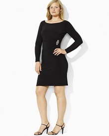 This sleek dress is tailored with an elegant boat neckline, shirring at the left waist and an encrusted broach exuding a chic, sophisticated style.