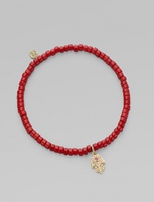 The hamsa, a traditional protective amulet, is encrusted with diamonds and accented with one ruby as it hangs from a stretchy strand of richly colored coral beads. Diamonds, 0.05 tcw Coral 14k yellow gold Diameter, about 2 (unstretched) Charm length, about ½ Imported