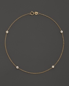 Diamond bezels sparkle from the stations on this dainty 14K yellow gold ankle bracelet.